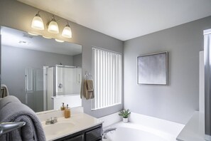 A modern bathroom with a large mirror, a bathtub, and a shower. - 3BR Home Near Las Vegas Strip | Pet Friendly (Las Vegas)