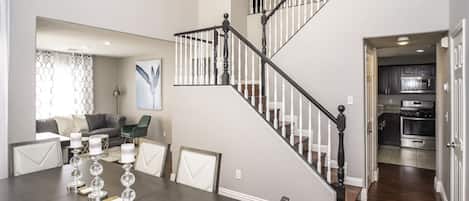 Ein modernes Interieur mit Essbereich, Treppe und Küche.