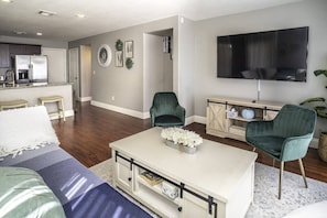 A modern living room with a sofa, two armchairs, a coffee table, and a TV.