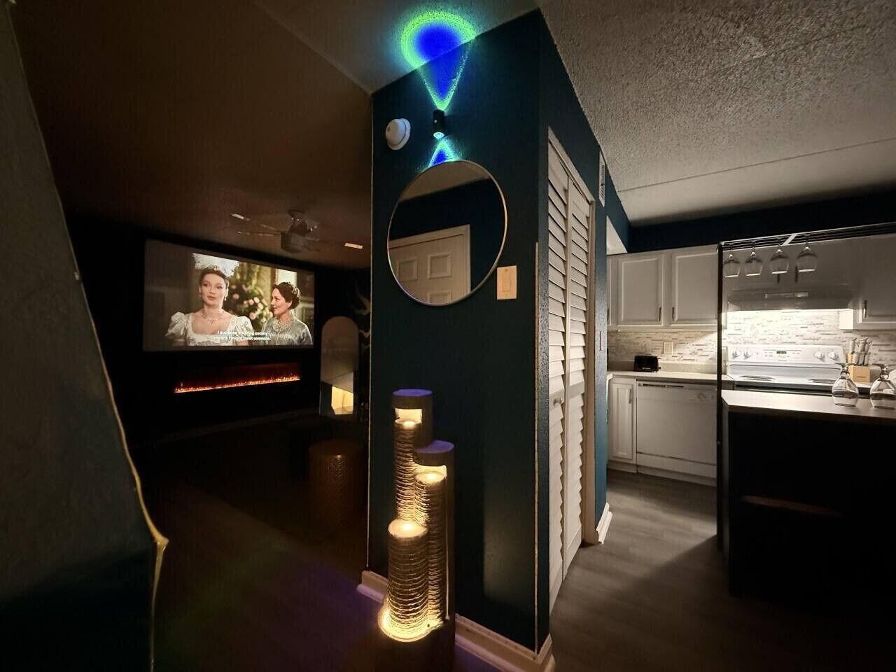 Un interior moderno con televisor, un espejo decorativo y una zona de cocina.