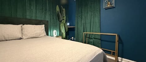 A bedroom with a bed, curtains, a bedside lamp, and a wall-mounted shelf.