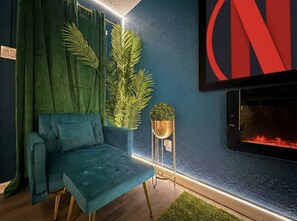 A modern living room with a blue sofa, green curtains, a small plant, and a fireplace. - Grand Teal Dynasty•Pool•Fireplace•Clean (Gulfport)
