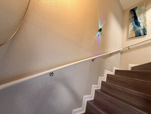 A staircase with a handrail and a wall-mounted light fixture.