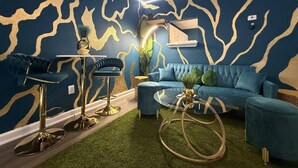 Uma sala de estar moderna com um sofá azul, uma mesa de centro redonda e um espaço bar com banquetas.