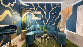 A modern living room with a blue sofa, a glass coffee table, and a blue armchair.