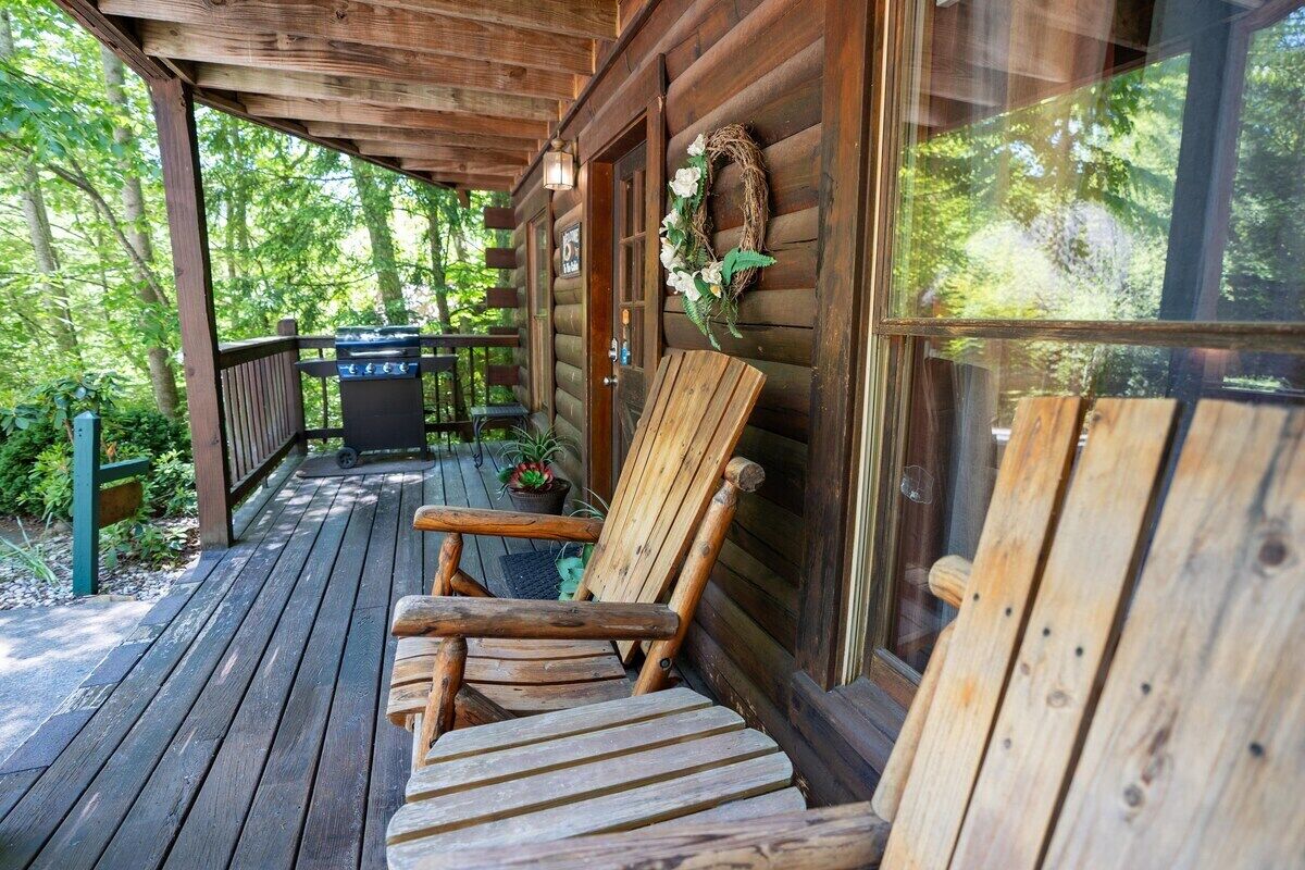A wooden deck with a bench, a barbecue grill, and a glass door with a wreath.