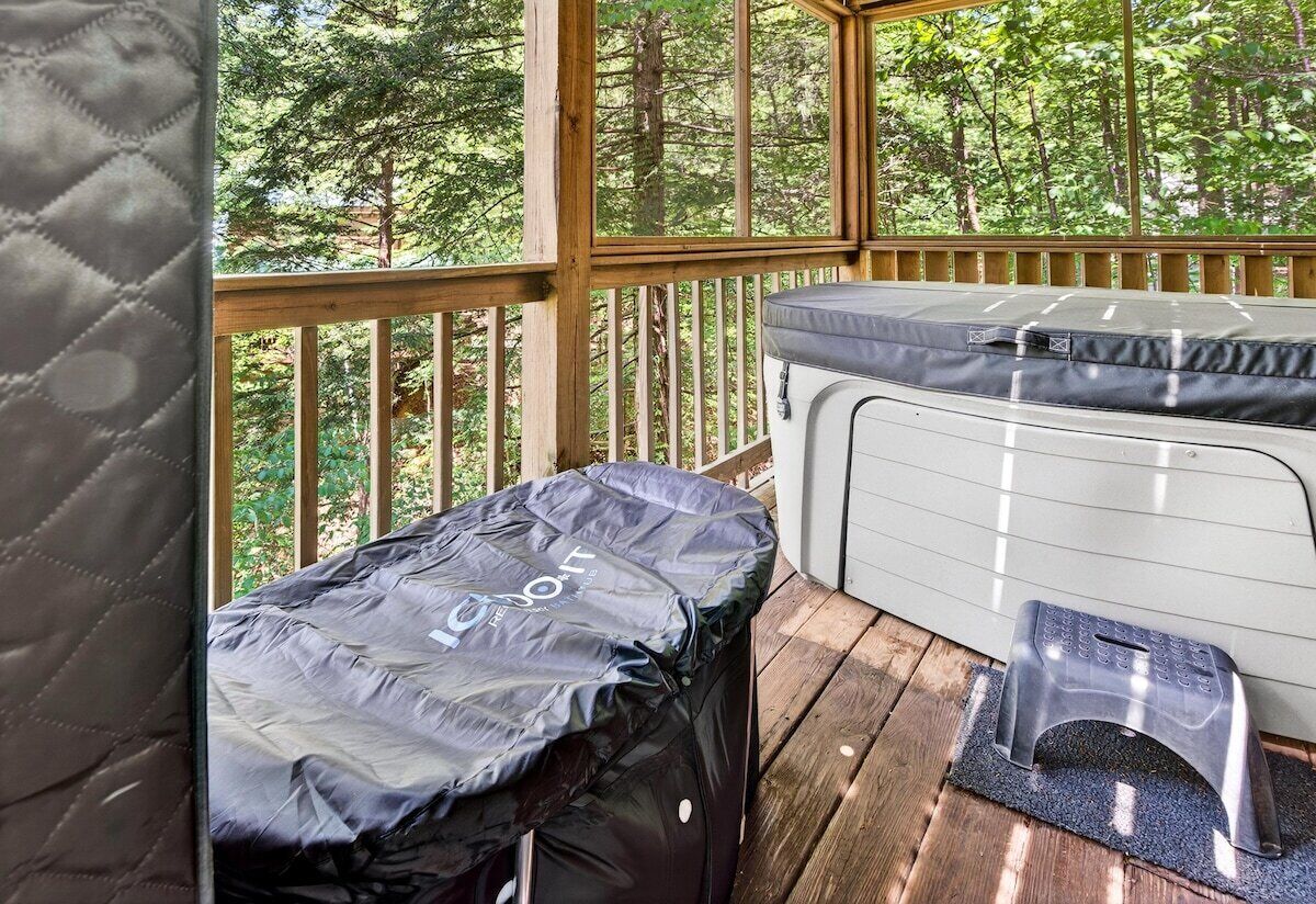 Un espace extérieur abrité, avec un banc et une table, entouré d’une terrasse en bois et d’arbres.