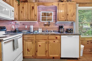 A kitchen with wooden cabinets, a microwave, a stove, a sink, and a dishwasher. - Hot Tub, Sauna, Pool Table, Free Dollywood, Spa (Gatlinburg)