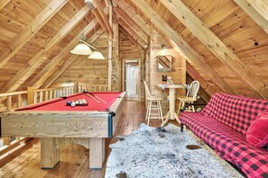 A cozy attic room with a pool table, a red sofa, and a cowhide rug. - Hot Tub, Sauna, Pool Table, Free Dollywood, Spa (Gatlinburg)