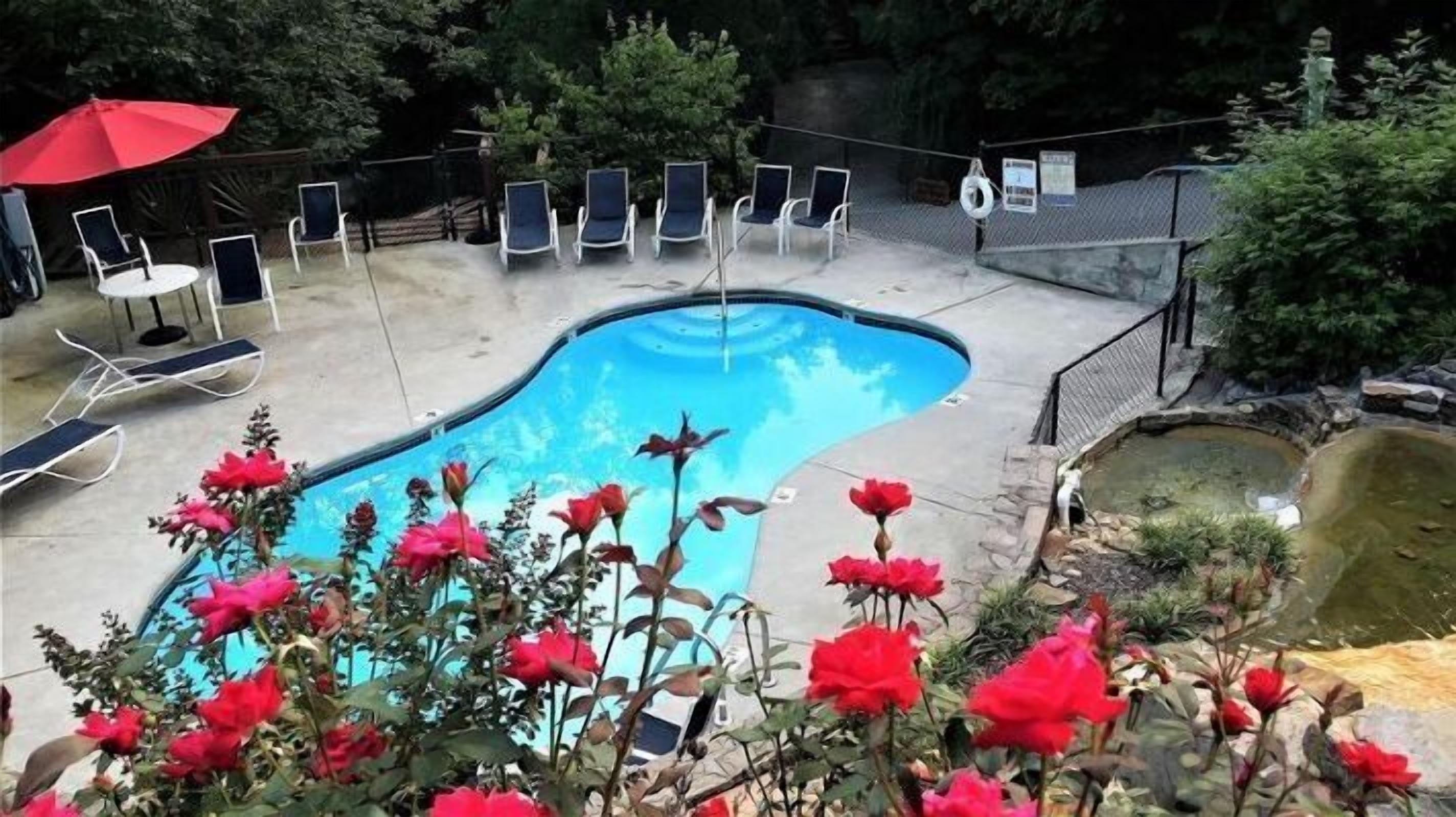A swimming pool with lounge chairs and a red umbrella.