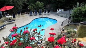 Ein Schwimmbecken mit Liegestühlen und einem roten Sonnenschirm.