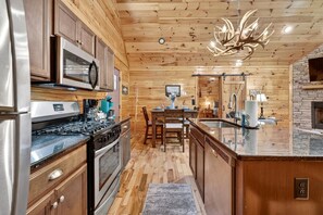 A kitchen with wooden walls, a central island, stainless steel appliances, and a chandelier. - Free Tickets,Sauna,Cold Plunge,Gatlinburg, 1 level (Gatlinburg)