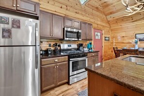 A kitchen with wooden walls, stainless steel appliances, and a granite countertop. - Free Tickets,Sauna,Cold Plunge,Gatlinburg, 1 level (Gatlinburg)