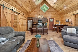 A log cabin interior with a dining area, kitchen, and two sofas. - Free Tickets,Sauna,Cold Plunge,Gatlinburg, 1 level (Gatlinburg)