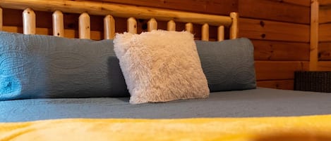 Una cama con cabecera de madera, dos almohadas y una colcha.