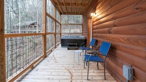 Een houten hut met terras, een bubbelbad en twee stoelen.