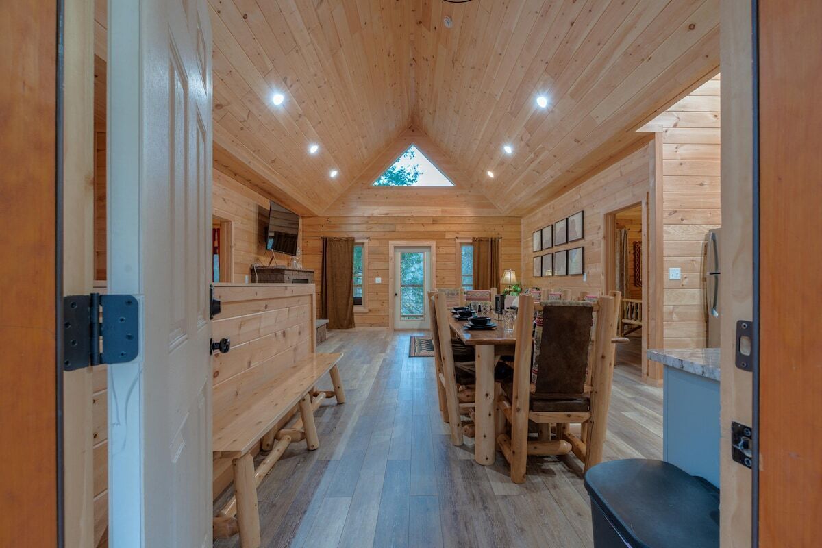 A wooden interior with a dining area, benches, and a central table.