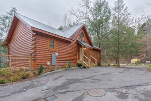 A log cabin with a metal roof, a front porch, and a paved driveway. - Hot Tub & Dolly Tickets - Gatlinburg Cabin Retreat (Gatlinburg)