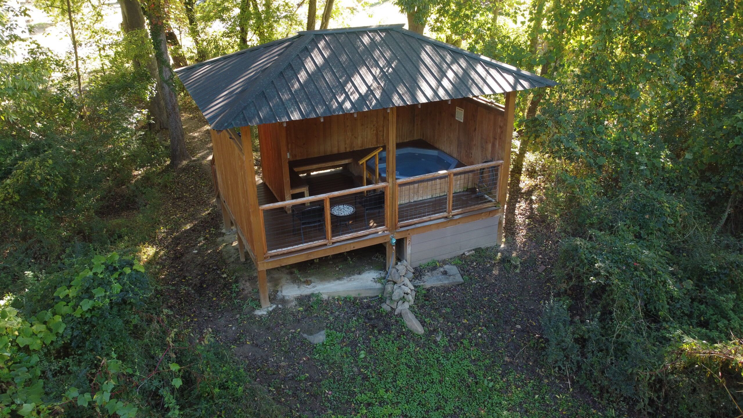 Une cabane en bois avec un toit en métal, un balcon et un jacuzzi.