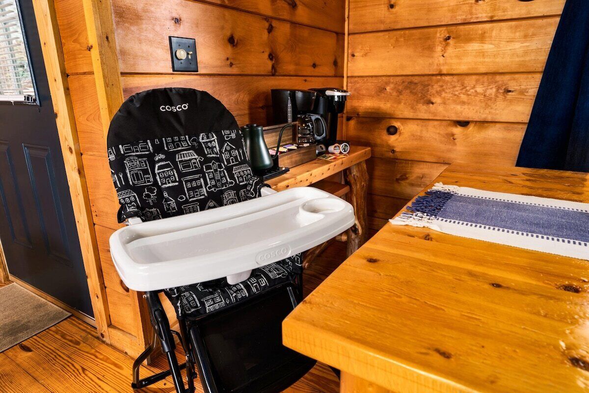 L’intérieur d’une cabane en bois comprend un coin cuisine, un évier blanc et une machine à café posée sur une table en bois.