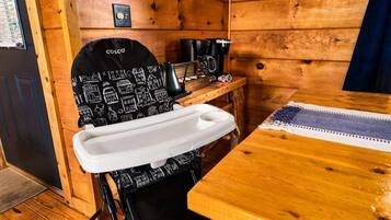 L’intérieur d’une cabane en bois comprend un coin cuisine, un évier blanc et une machine à café posée sur une table en bois.