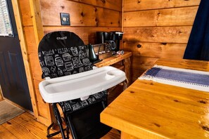 Een houten cabin met een kitchenette, een wit spoelgedeelte en een koffiezetapparaat op een houten tafel.