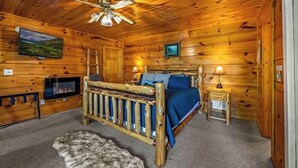 Une chambre située dans un chalet en rondins, avec un lit en bois, une télévision et une cheminée.