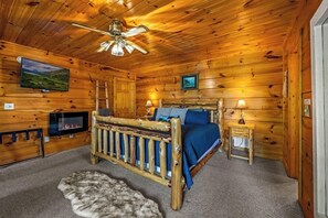 Une chambre située dans un chalet en rondins, avec un lit en bois, une télévision et une cheminée.