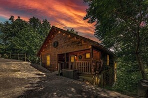 A rustic cabin with a wooden exterior, a porch, and a small front yard. - Romantic, Hot Tub, Free Dollywood + Hot Spring Spa (Sevierville)