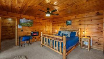 Une chambre dans une cabane en bois, comprenant un lit, un bureau, une chaise et un ventilateur de plafond.