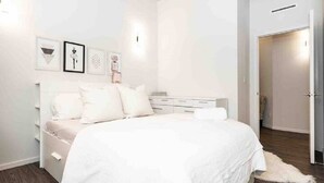 A bedroom with a bed, bedside tables, and a wardrobe. - Spacious Exchange District Condo | 1 Bed | 1 Bath | (Winnipeg)