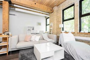 Un salon moderne comprenant un canapé, un lit à baldaquin, une table basse et un bureau avec une lampe.