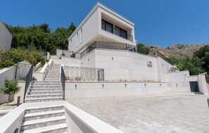 A modern two-story building with a flat roof, a staircase leading to the entrance, and a paved driveway. - Gorgeous home in Mlini with sauna (Mlini)