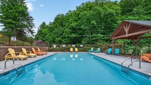 Une piscine avec des chaises longues et un espace de repos abrité.