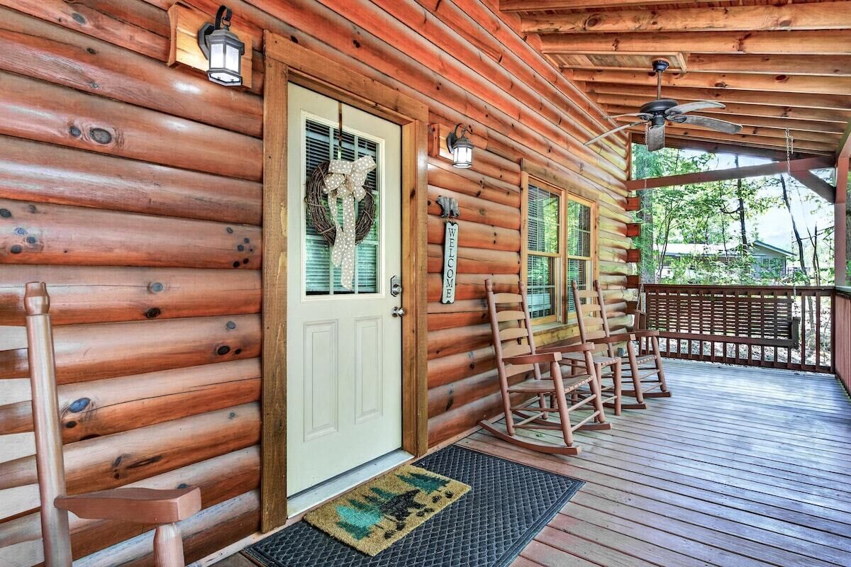 Une cabane en bois avec un porche, une pancarte de bienvenue et une chaise berçante.