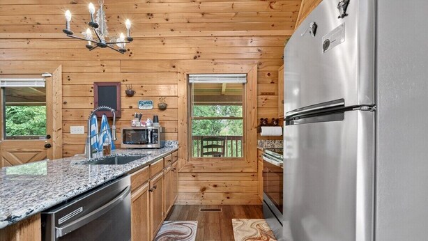 Une cuisine avec des murs en bois, un réfrigérateur en acier inoxydable, un four à micro-ondes et un plan de travail en granit.