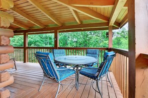 A covered outdoor seating area with a round table and blue chairs, surrounded by a wooden deck and a wooden fence. - Sauna,Cold Plunge,Hot Tub,Free Tickets,Resort Pool (Sevierville)