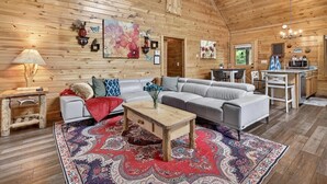 Un intérieur en bois avec un canapé, une table basse et un tapis à motifs.