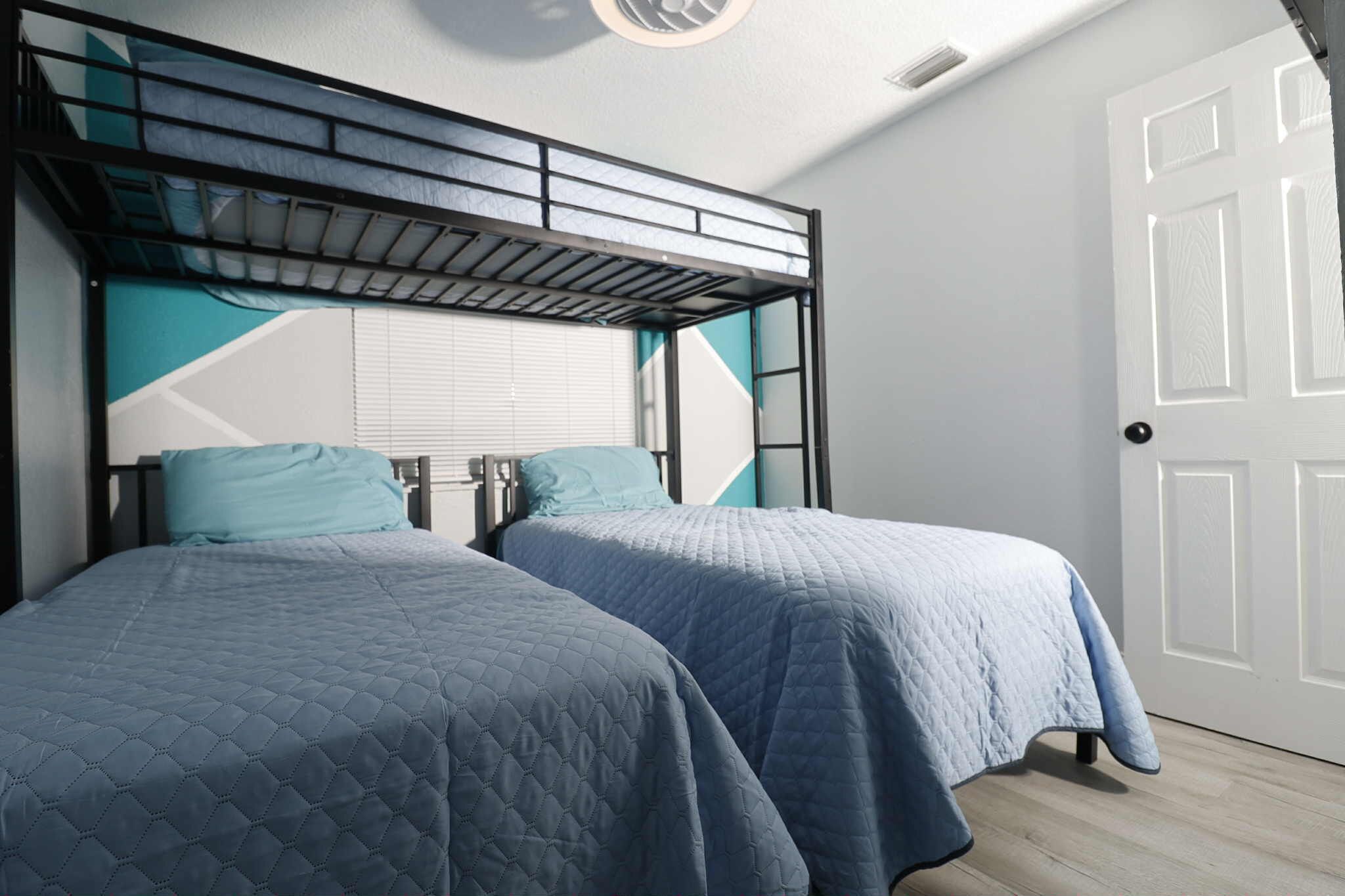 Une chambre avec deux lits, un lit superposé et une porte blanche.