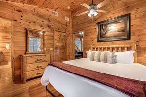 A wooden cabin room with a bed, dresser, and a ceiling fan. - Free Dollywood, Hot Tub, Firepit, Pool Table, Spa (Gatlinburg)