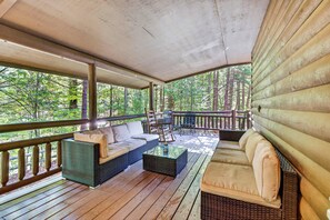 A covered outdoor seating area with wicker furniture and a view of the forest. - Free Dollywood, Hot Tub, Firepit, Pool Table, Spa (Gatlinburg)