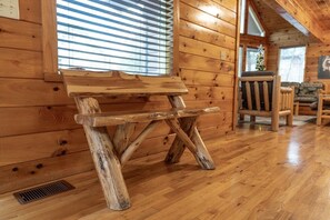 A rustic wooden bench with a slatted seat and backrest, positioned against a wooden wall with a window. - Free Dollywood, Hot Tub, Firepit, Pool Table, Spa (Gatlinburg)