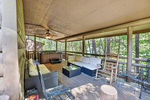 A covered outdoor seating area with a sofa, chairs, and a hot tub. - Free Dollywood, Hot Tub, Firepit, Pool Table, Spa (Gatlinburg)