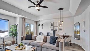 Una sala de estar moderna con un sofá gris, una mesa de centro y una zona de comedor con una mesa redonda y sillas.