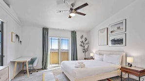Habitación de hotel con cama, escritorio, silla y vistas por la ventana.