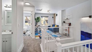 Un apartamento moderno con una escalera, una sala de estar con un sofá azul y vistas al exterior.