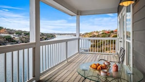 Ein Balkon mit einem Glastisch, gedeckt für das Frühstück, mit Blick auf einen Fluss und entfernte Gebäude.