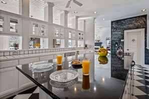 A modern kitchen with a central island, white cabinetry, and a black and white checkered floor. - Lakefront Dream/Sleeps 16+/Pool/HotTub/Slides/Dock (Marble Falls)