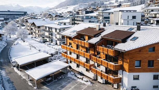 Un hôtel à plusieurs étages doté de balcons, d’un parking couvert et surplombant un paysage montagneux.