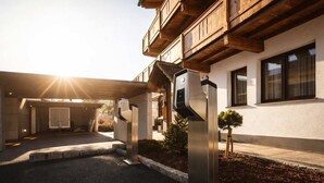 Un bâtiment moderne doté d’un porche, d’un petit arbre et de deux structures métalliques.